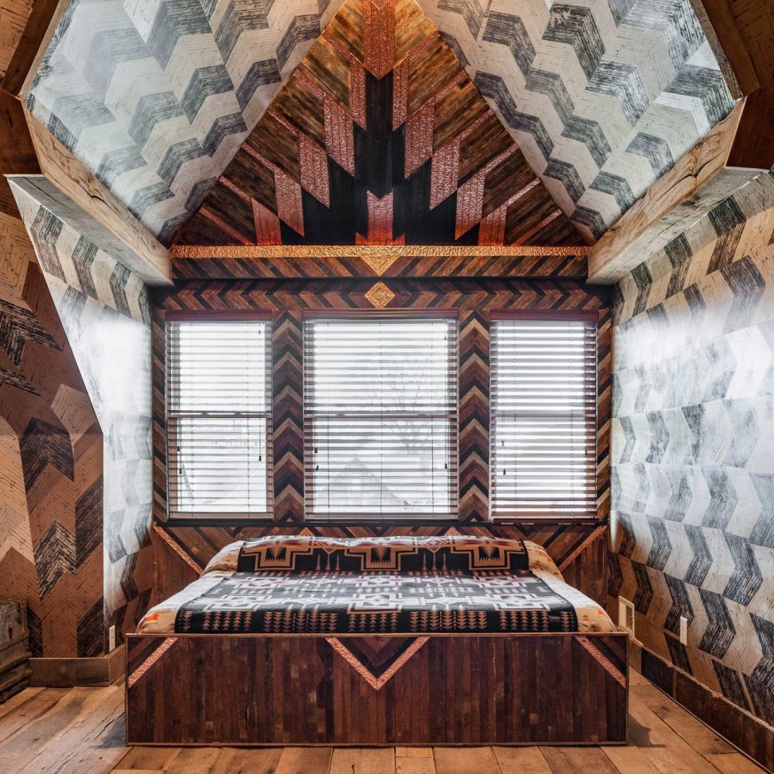 Queen sized bed inside The Lions Den room of Urban Cowboy Nashville. The bed is placed in a cozy area of this Penthouse room, with a 14 foot wooden headboard. Photo taken by Ben Fitchett.