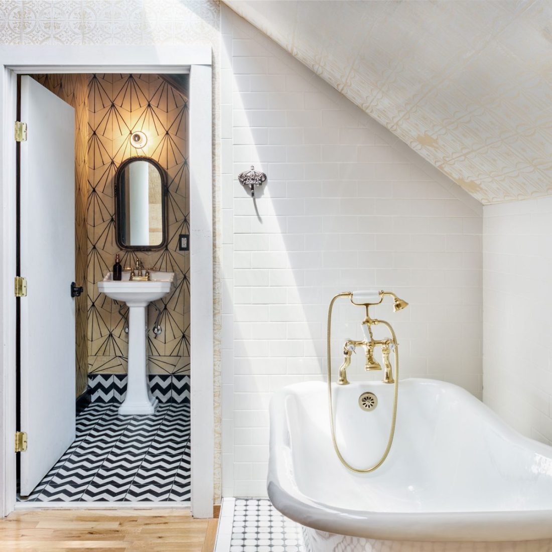 Sleek white bathtub under the A-frame of The Urban Cowboy Nashville. Beyond the bathroom, a door leads to a tiled wash room.