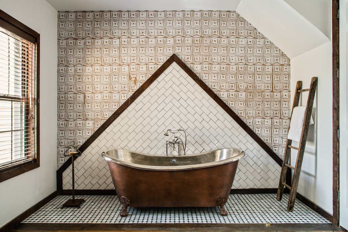 The clawfoot bathtub of the Private Treehouse townhouse inside Urban Cowboy. The tilework makes a triangle on the wall, where the claw foot bathtub rests.