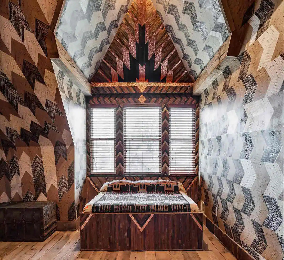 Queen sized bed inside The Lions Den room of Urban Cowboy Nashville. The bed is placed in a cozy area of this Penthouse room, with a 14 foot wooden headboard. Photo taken by Ben Fitchett.